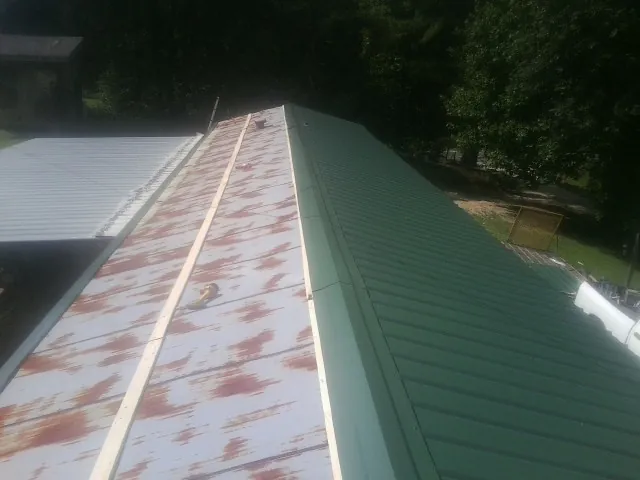 Old rusted panels beside newly installed green metal roofing — Wind Damage Roof Repair by Roofing Brothers in Liberty Lake