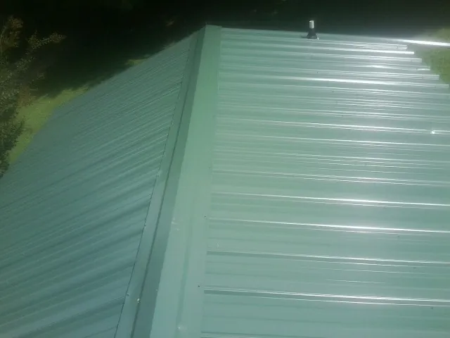 New green metal panels meeting at the ridge of a roof — Flat Roof Repair work by our crew in Liberty Lake