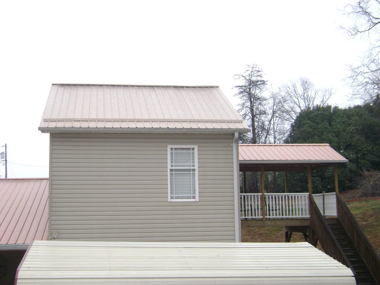 Tan metal roofs on a two story addition and attached porch, from a Roof Replacement job in Liberty Lake