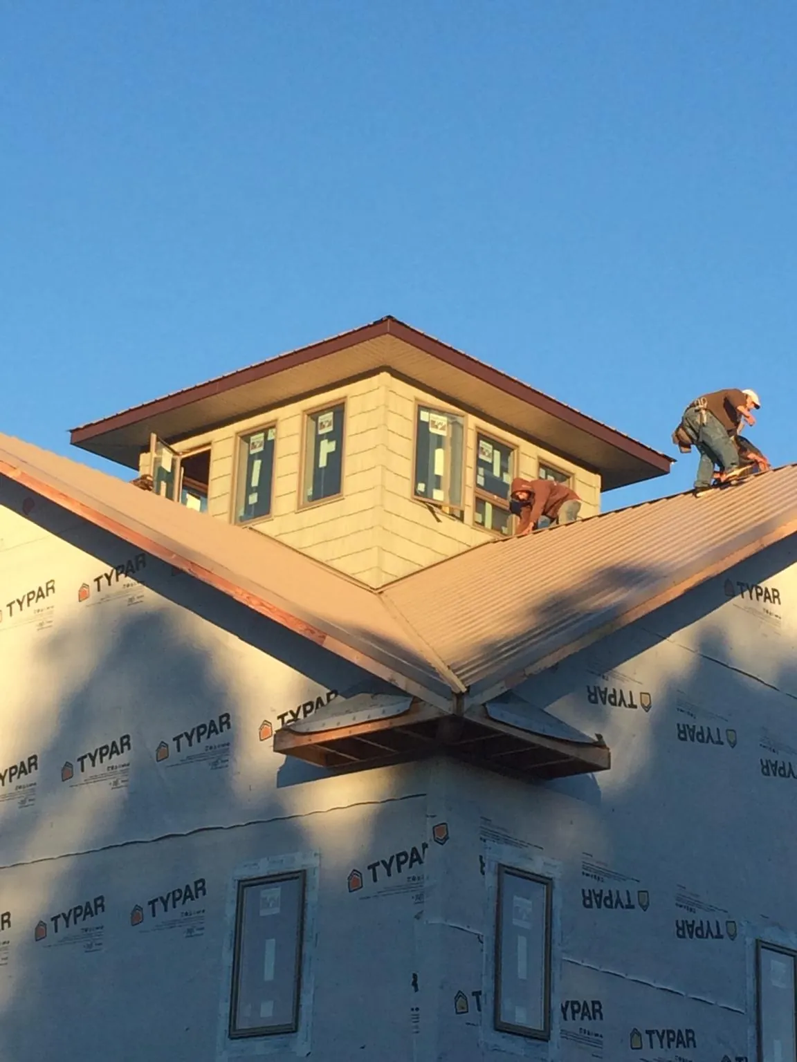 Roofers working around a rooftop cupola on a new metal roof at sunset — Roof Waterproofing in Liberty Lake by Roofing Brothers